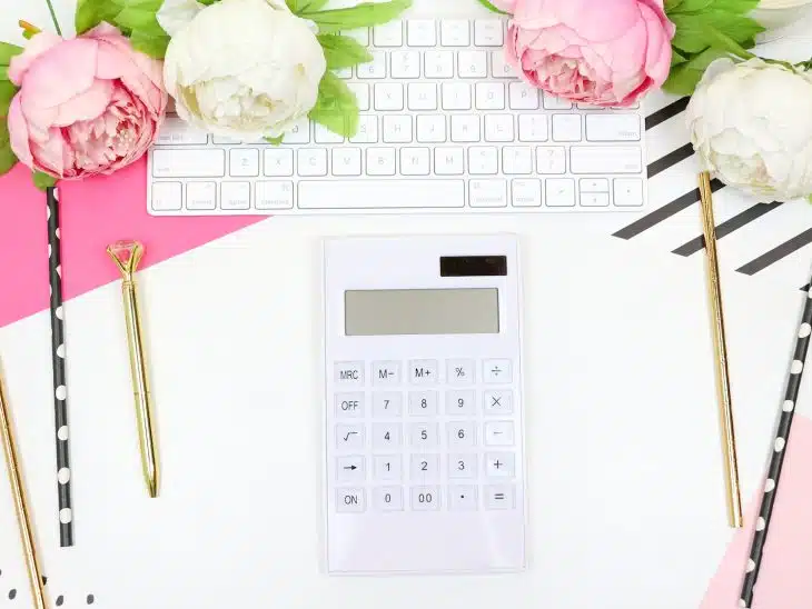 white calculator beside pink rose
